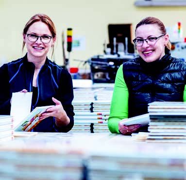 Konfektion: Melinda Mate (links) und Jolanta Strazdawskiene stecken per Hand Papp-Pfeile in Lesebücher für Erstklässler.